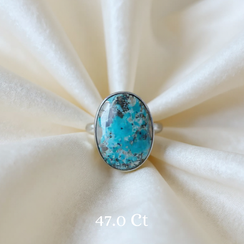 Turquoise ring with silver band on a beige fabric background