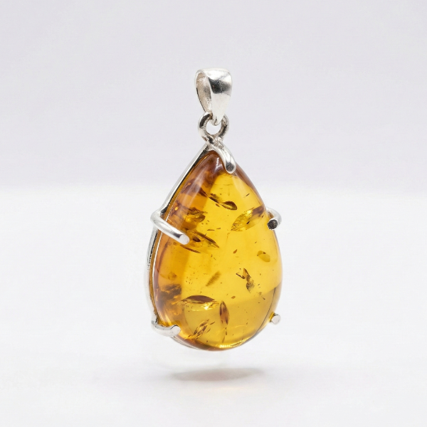 Teardrop-shaped amber pendant with silver setting on a white background