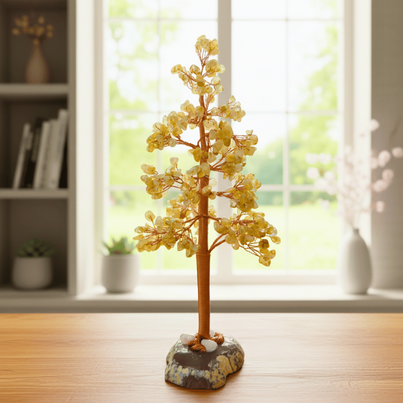 Decorative citrine stone tree with yellow beads on a stone base in a room with a window and shelves.