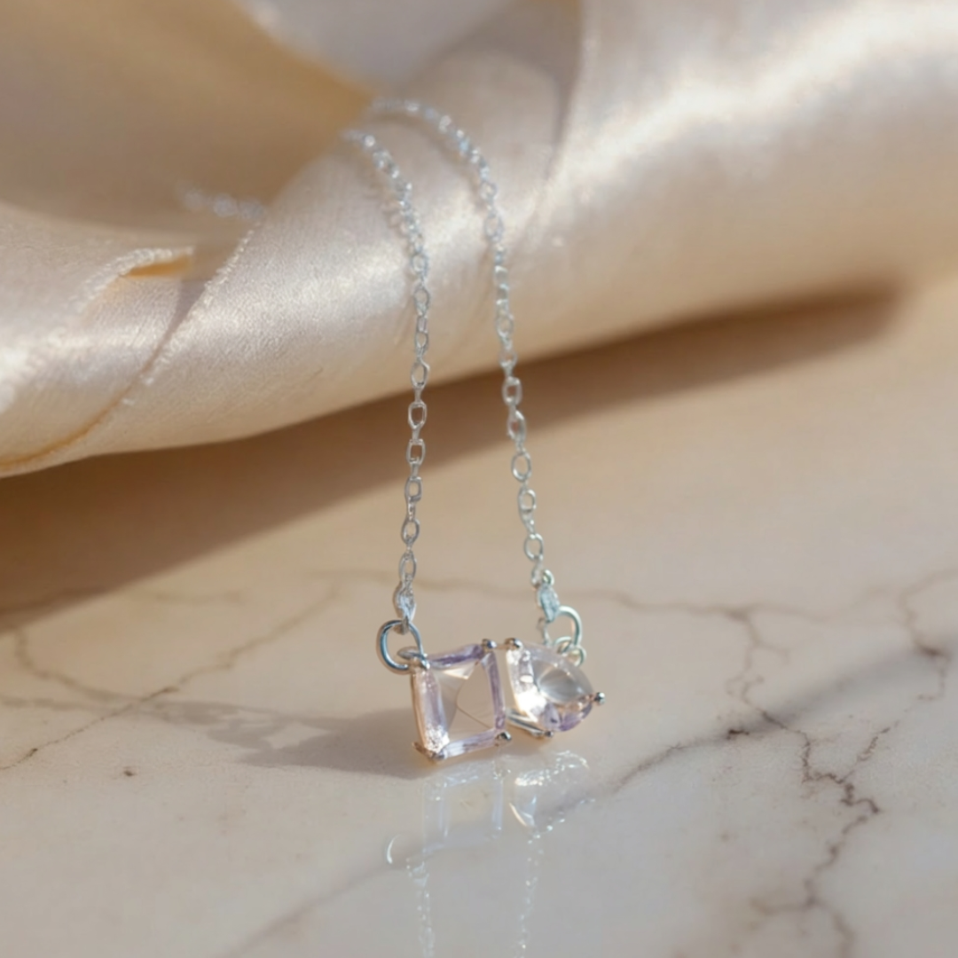 Silver necklace with a clear gemstone pendant on a marble surface