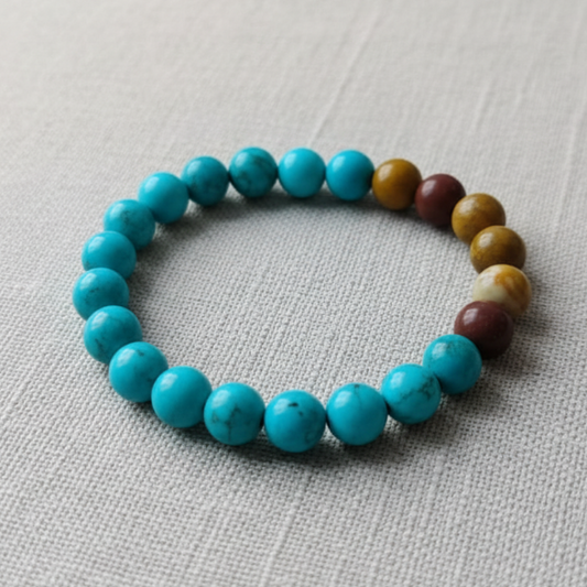 Beaded bracelet with turquoise beads and multicolored accents on a light gray fabric background
