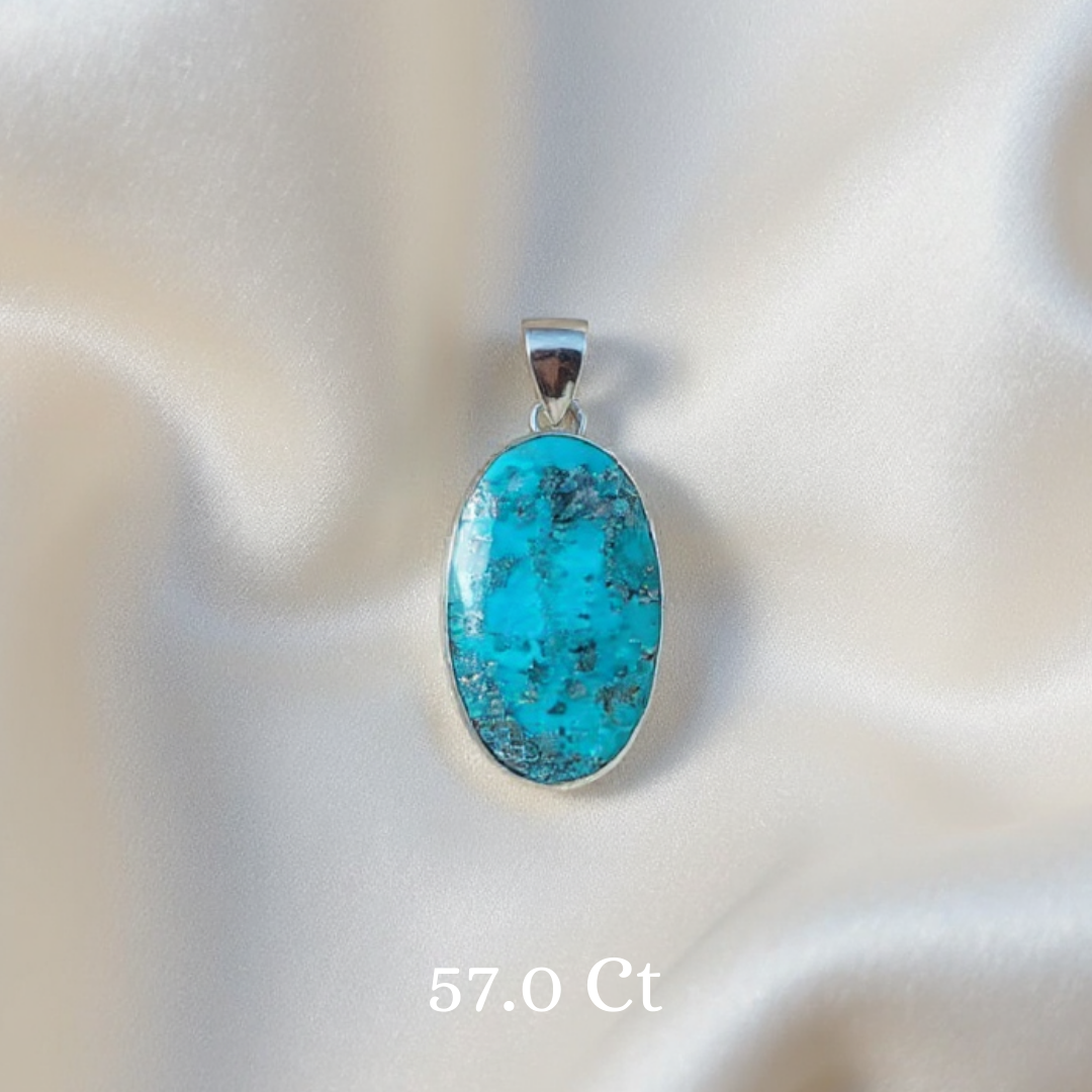 Turquoise pendant with silver setting on a soft white background