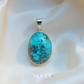 Turquoise pendant with silver frame on a white fabric background