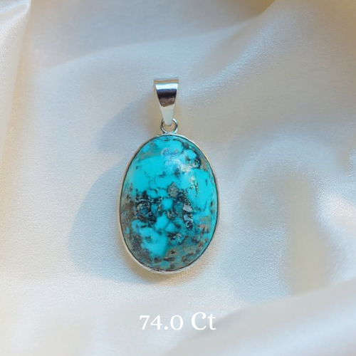 Turquoise pendant with silver frame on a white fabric background