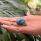 Turquoise stone on a person's palm with a blurred green leafy background