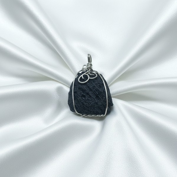 Black stone pendant with silver wire wrapping on a white satin background