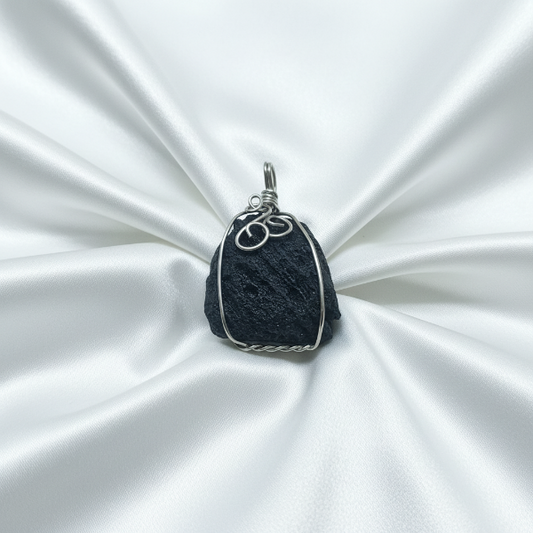 Black stone pendant with silver wire wrapping on a white satin background