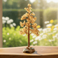 Decorative citrine crystal tree on a wooden surface with a blurred natural background