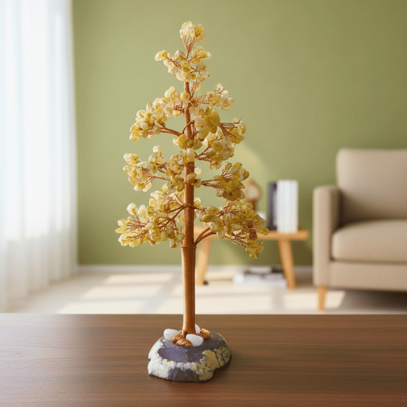 Decorative citrine crystal tree sculpture on a wooden surface with a blurred living room background