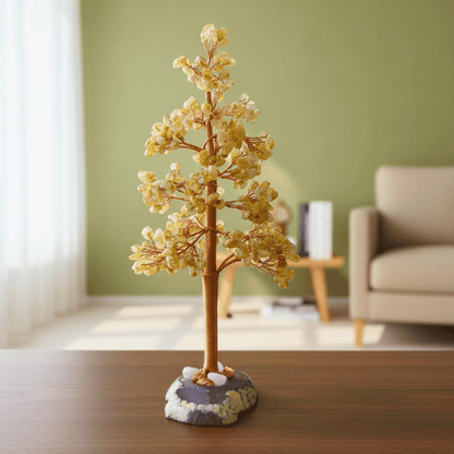 Decorative citrine crystal tree sculpture on a wooden surface with a blurred living room background
