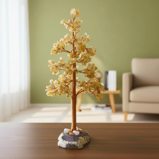 Decorative citrine crystal tree sculpture on a wooden surface with a blurred living room background