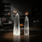 Two crystal towers on a wooden surface with a blurred background of candles and shelves.