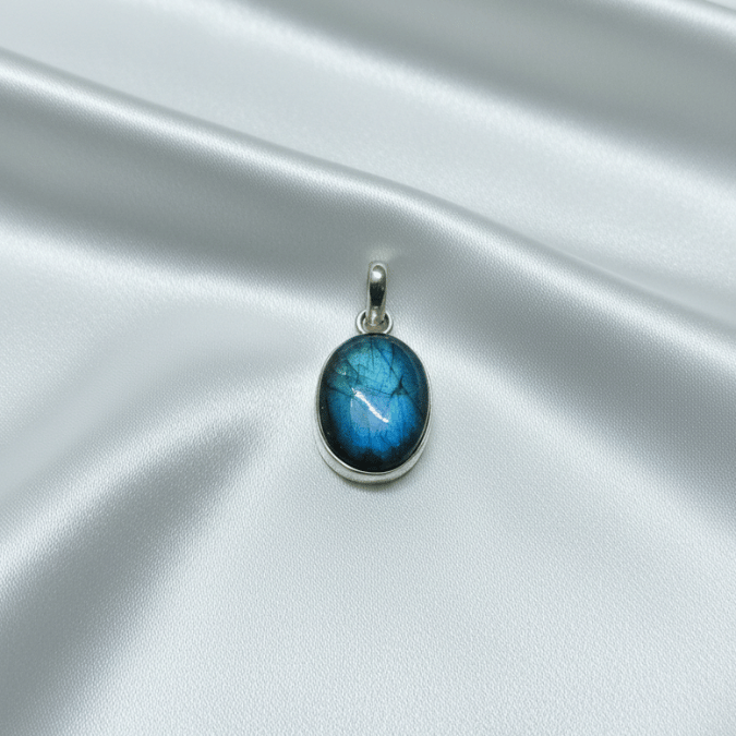 labradorite stone pendant on a silver chain against a satin surface