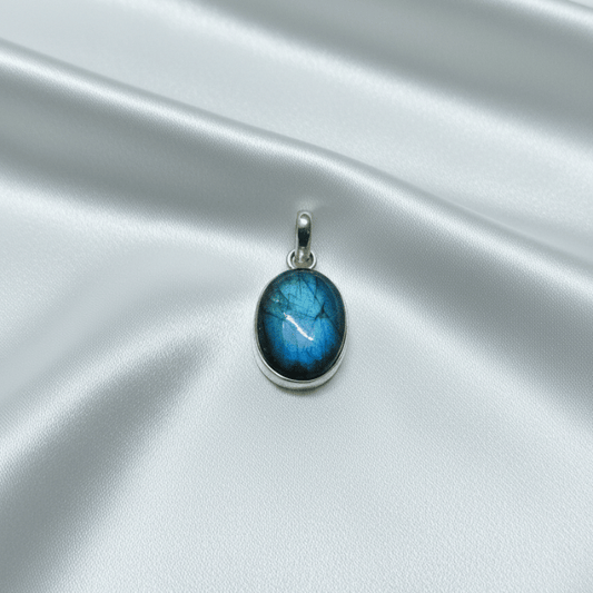 labradorite stone pendant on a silver chain against a satin surface