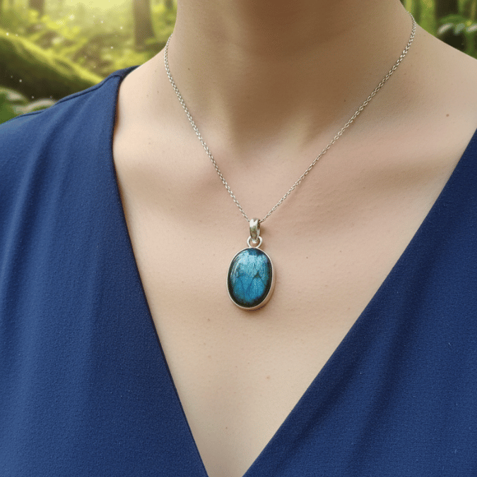 Blue pendant necklace on a person wearing a blue top with a blurred green background