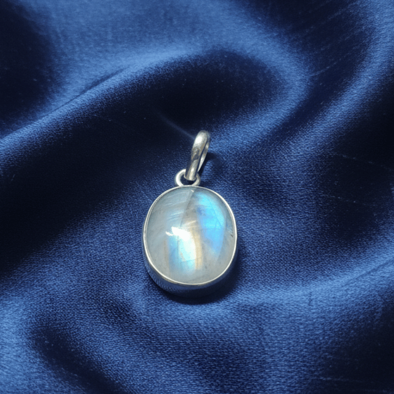 Silver pendant with a rainbow moonstone on a blue satin background