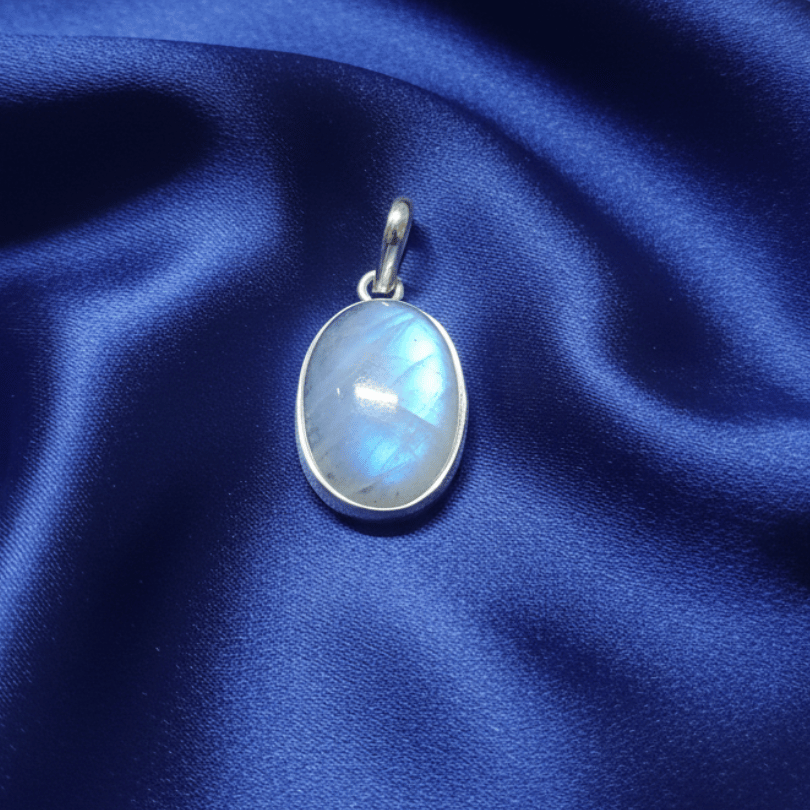 Silver pendant with a moonstone gemstone on a blue satin background