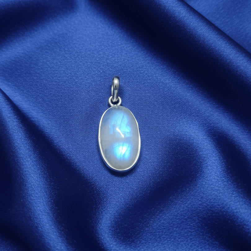 Silver pendant with a blue gemstone on a blue satin background