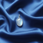 Silver pendant with a rainbow moonstone on blue satin fabric