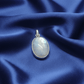 Silver pendant with a moonstone crystal stone on a blue fabric background