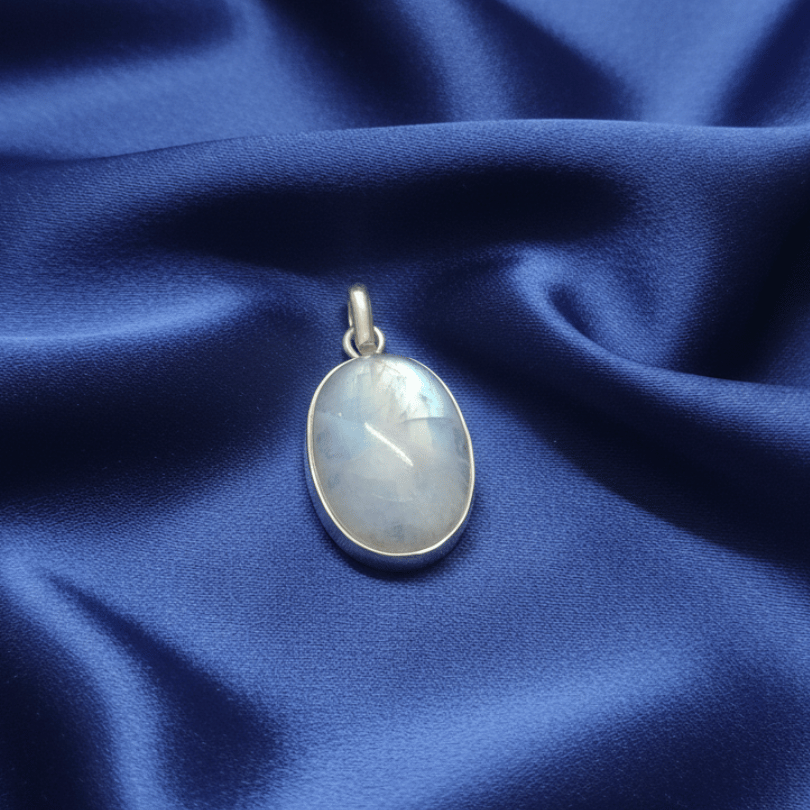 Silver pendant with a moonstone crystal stone on a blue fabric background