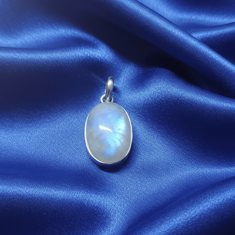 Silver pendant with a blue gemstone on a blue satin background