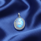 Silver pendant with a blue gemstone on a blue satin background