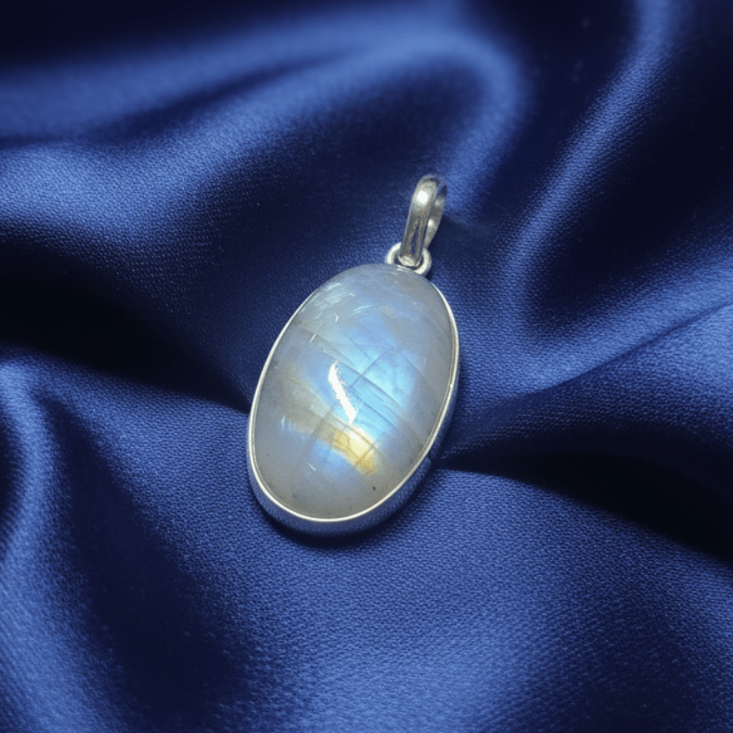 Silver pendant with a rainbow moonstone on a blue satin background