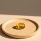 Yellow amber stone on a wooden plate with a neutral background