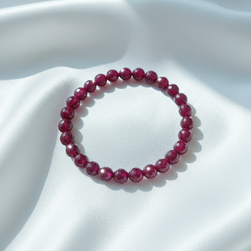 Red beaded bracelet on a white fabric background