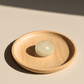 Wooden plate with a round, light-colored crystal stone on a beige background
