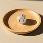 Wooden bowl with a marble-like crystal on a beige background