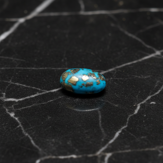 Turquoise stone with gold inclusions on a black textured surface