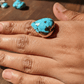 Turquoise stone ring on a hand with a wooden background